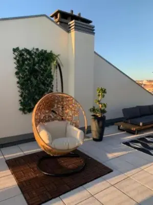 a wicker chair sitting on top of a patio at Amazing Penthouse with a Terrace in Porto