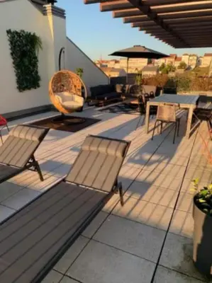 a patio with benches and tables and an umbrella at Amazing Penthouse with a Terrace in Porto