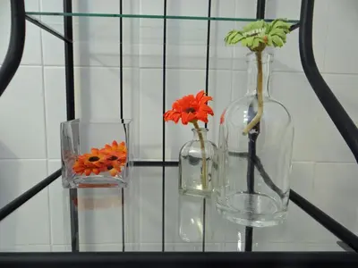 two glass vases with flowers in them sitting on a shelf at Alegria Apartment Porto Downtown in Porto