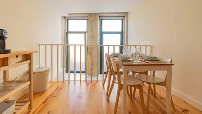 a dining room with a table and chairs and two windows at Delightful Duplex by LovelyStay in Porto