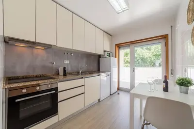 a kitchen with white cabinets and a table with wine glasses at Rooftop Stylish by Hosty in Porto