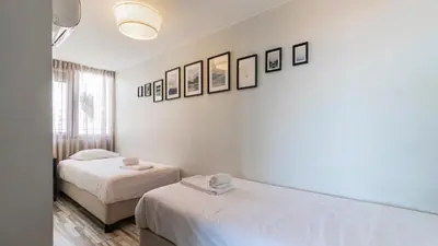 two beds in a white room with pictures on the wall at Abadia by LovelyStay in Porto