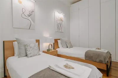 two beds in a room with white walls at Romantic Luxury House w Captivating Outdoor Patio in Porto