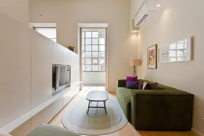 a living room with a green couch and a tv at Ateneu Boutique Townhouse Bolhão in Porto
