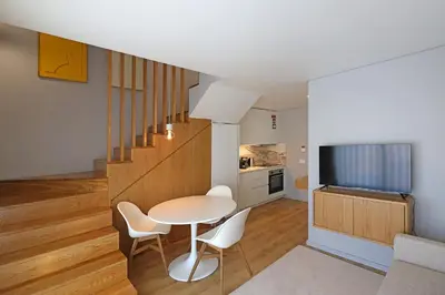 a kitchen and dining room with a white table and chairs at FLH Boavista Wooden Duplexes in Porto