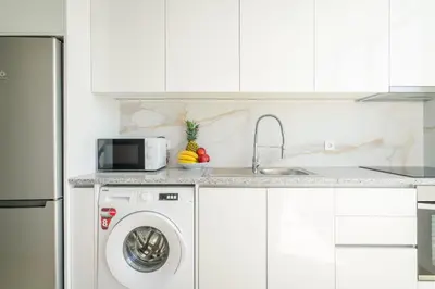 a white kitchen with a washing machine and a sink at Host Wise - Peaceful Sunny Flat - Ace Location in Porto