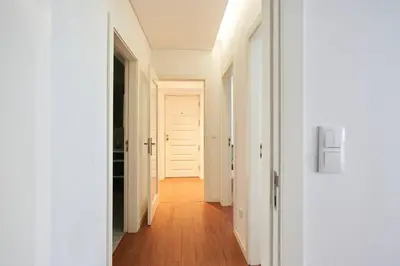 a hallway with white doors and a wooden floor at So Family Porto in Porto