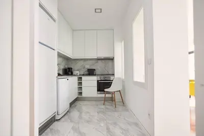 a kitchen with white cabinets and a chair in it at So Family Porto in Porto