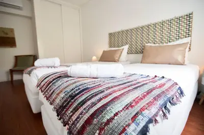 a large white bed with a colorful blanket on it at So Family Porto in Porto