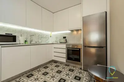a kitchen with white cabinets and a stainless steel refrigerator at Trendy Porto in Porto