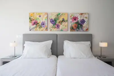 two beds in a bedroom with two paintings on the wall at Comfy Porto in Porto