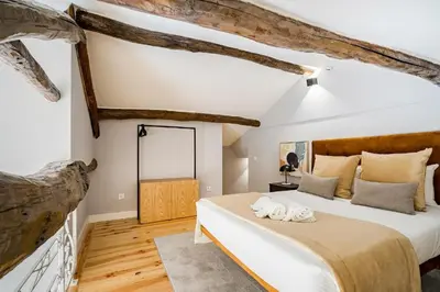 a bedroom with a large bed and wooden beams at GuestReady - Comendador Sto Ildefonso in Porto