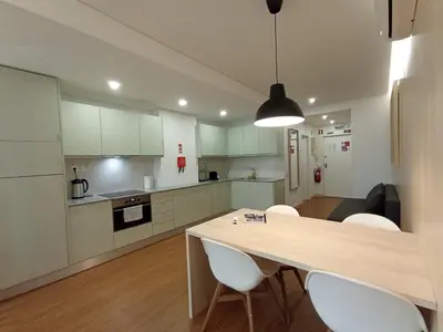 a kitchen with white cabinets and a table and chairs at 715 Galé Apartment Wi-Fi, Estacionamento in Porto