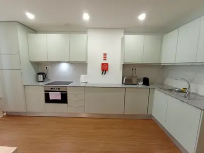 a white kitchen with white cabinets and a wooden floor at 715 Galé Apartment Wi-Fi, Estacionamento in Porto
