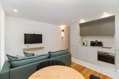 a living room with a green couch and a kitchen at GuestReady - Cozy Vitoria Apartment in Porto