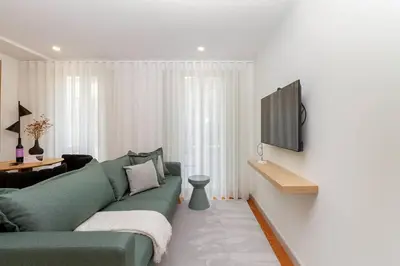 a living room with a green couch and a flat screen tv at GuestReady - Cozy Vitoria Apartment in Porto