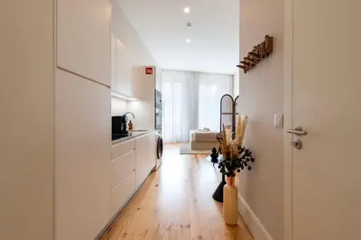 a kitchen with white cabinets and a hard wood floor at Ando Living - Flores 200 House in Porto