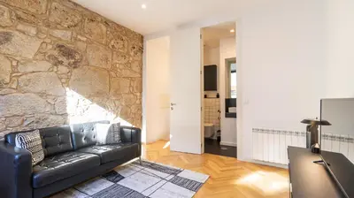 a living room with a leather couch and a stone wall at Premium Duplex in Bonfim by LovelyStay in Porto