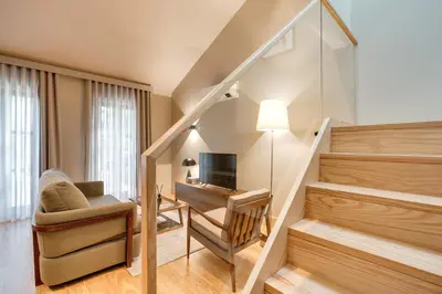 a room with a staircase with a chair and a television at AVUS M Suites and Apartments by DA'HOME in Porto