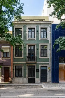 a green building with black doors on a city street at AVUS M Suites and Apartments by DA'HOME in Porto