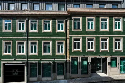 a green building with white windows on a street at Vincci Bonjardim in Porto