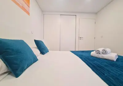 a white bed with blue pillows and towels on it at Alegria Stay in Porto