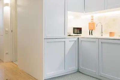 a white kitchen with white cabinets and a sink at ORM Padrão Apartment in Porto