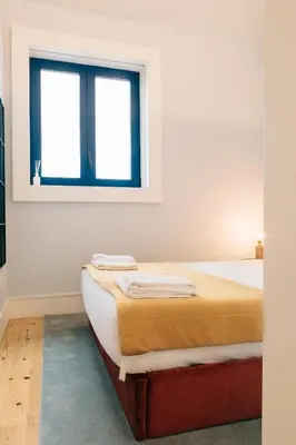 a bed in a white room with a window at ORM Padrão Apartment in Porto