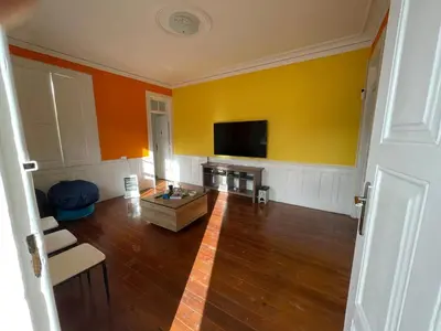 a living room with a flat screen tv on a yellow wall at Owls Hostel Ildefonso in Porto