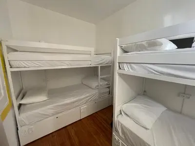 a room with white bunk beds in a room at Owls Hostel Ildefonso in Porto