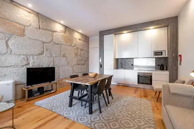 a living room with a table and a stone wall at VIVA Aliados Downtown in Porto