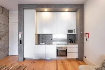 a kitchen with white cabinets and a wooden floor at VIVA Aliados Downtown in Porto