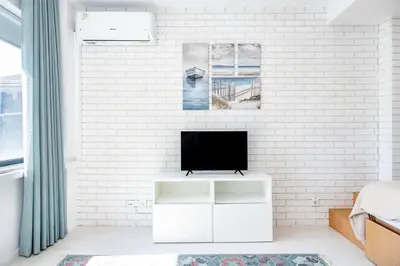a white bedroom with a tv on a white brick wall at VIVA Marquês Studio in Porto