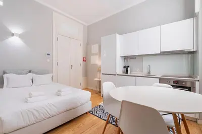 a white room with a white bed and a table at VIVA Arts Cozy Studio in Porto