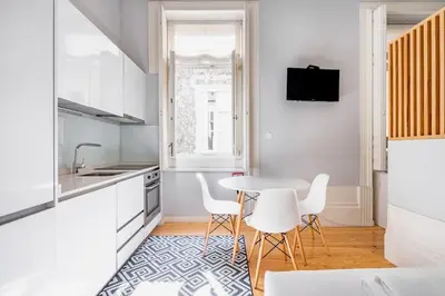 a kitchen with white cabinets and a table and chairs at VIVA Arts Cozy Studio in Porto