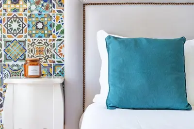 a blue pillow sitting on a bed next to a wall at VIVA Mosaics Studio in Porto