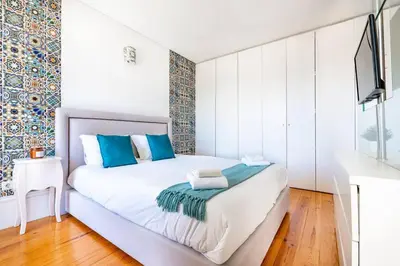 a bedroom with a white bed with blue pillows at VIVA Mosaics Studio in Porto