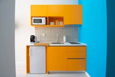 a small kitchen with orange cabinets and a white refrigerator at Leote House - Studio 4 in Porto