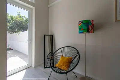 a chair with a yellow pillow in a room with a window at Leote House - Studio 4 in Porto