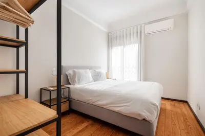 a bedroom with a bed with white sheets and a window at Rivoli Apartments in Porto