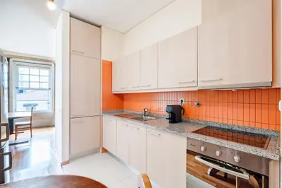 a kitchen with white cabinets and an orange wall at VIVA Old Franciscan Studio in Porto