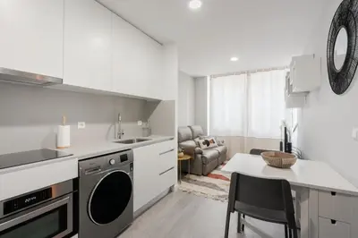 a white kitchen with a sink and a table at Great Location very Central Boavista in Porto