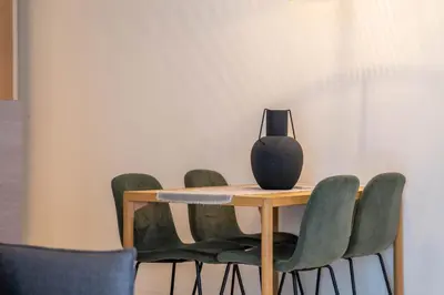 a table with green chairs and a vase on it at The Priest's Home by LovelyStay in Porto