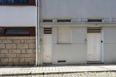 two white garage doors on the side of a building at GuestReady - Warm and Inviting flat with balcony in Porto