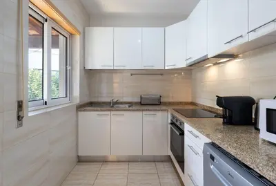 a kitchen with white cabinets and a sink at GuestReady - Warm and Inviting flat with balcony in Porto