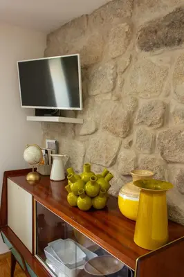 a table with a tv on a stone wall at ORM Santana Apartment in Porto