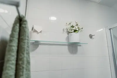 a glass shelf in a bathroom with a vase of flowers at Douro Garden - Authentic Portuguese Guesthouse in Vila Nova de Gaia