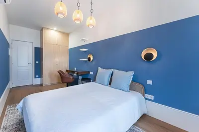 a bedroom with a blue wall and a white bed at L'Atelier by Upperground in Porto