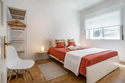 a white bedroom with a bed and a window at Oliveira Monteiro Flat in Porto