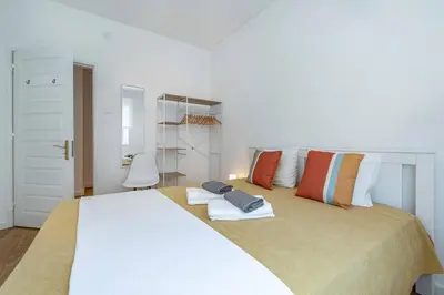 a white bedroom with a large white bed with pillows at Oliveira Monteiro Flat in Porto